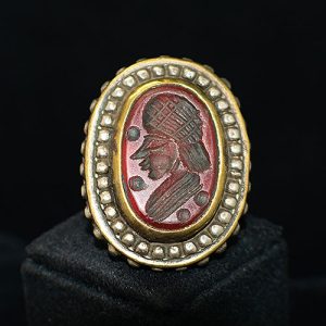 Anillo sello de plata de estilo oriental con un ágata tallada con la figura de un hombre de casta noble y de acabados en bronce y plateados con textura matizada y tosca
