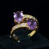 Anillo tú y yo de oro amarillo de 18k con una amatista oval en cada extremo y circonitas decorando el resto de la pieza.