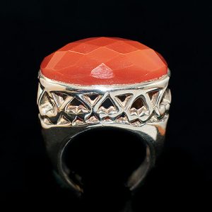 Anillo de plata con una cornalina central con facetas y brazo de acabados calados y lisos