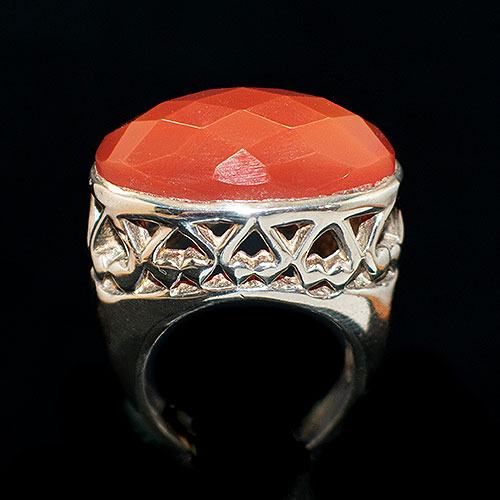 Anillo de plata con una cornalina central con facetas y brazo de acabados calados y lisos