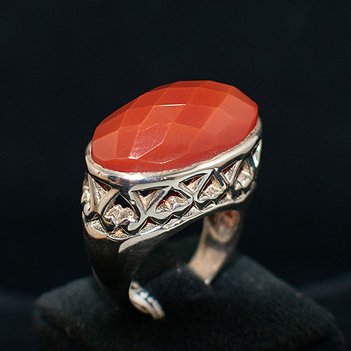 Anillo de plata con una cornalina central con facetas y brazo de acabados calados y lisos